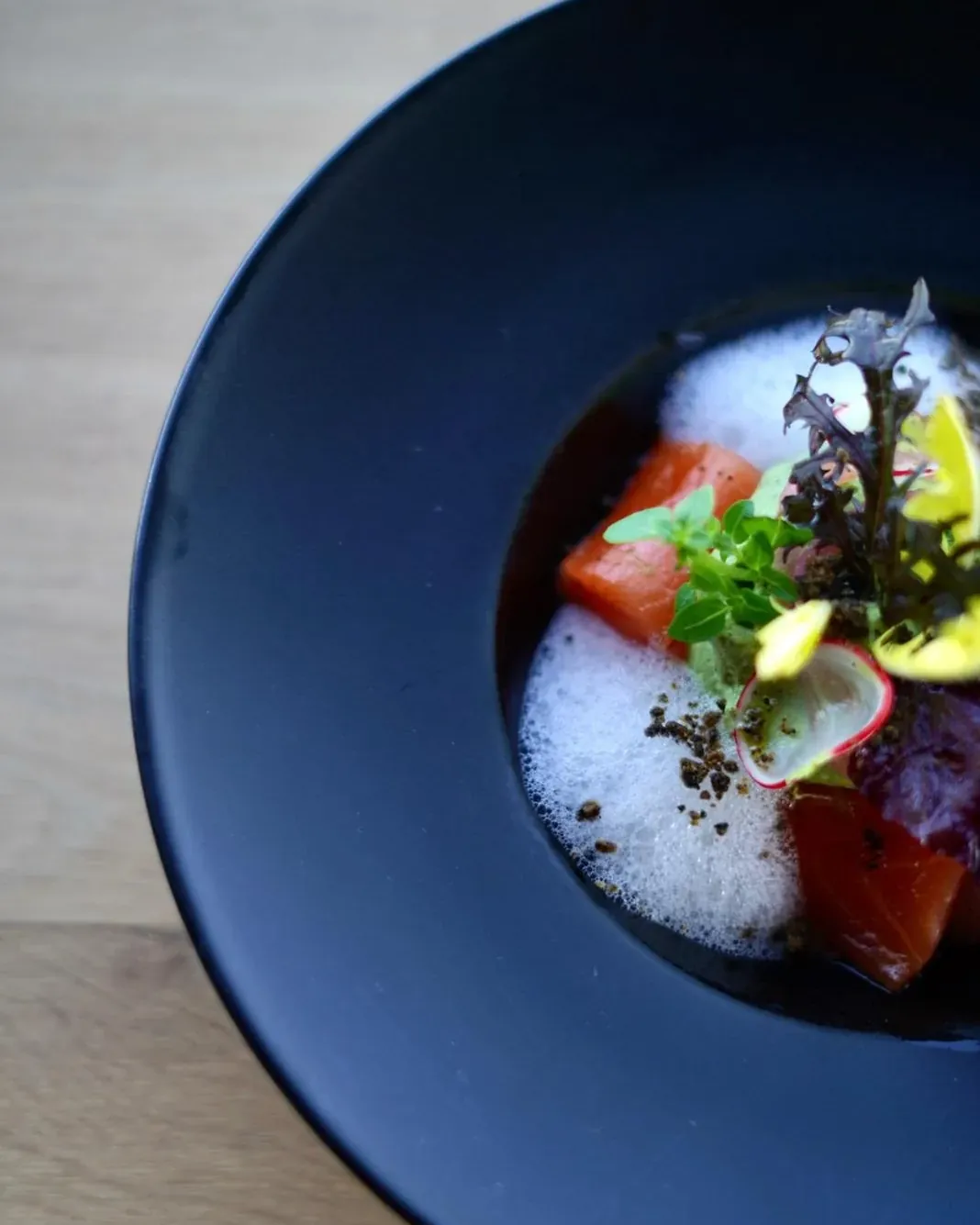 Cured fish, tomato and foam on a blue plate